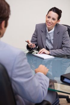 Smiling young businesswoman with notepad in negotiation