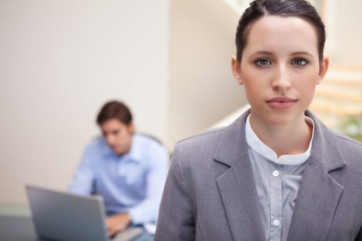 Young businesswoman with colleague on his laptop behind her