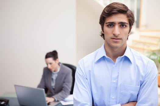 Young businessman with colleague on her notebook behind him