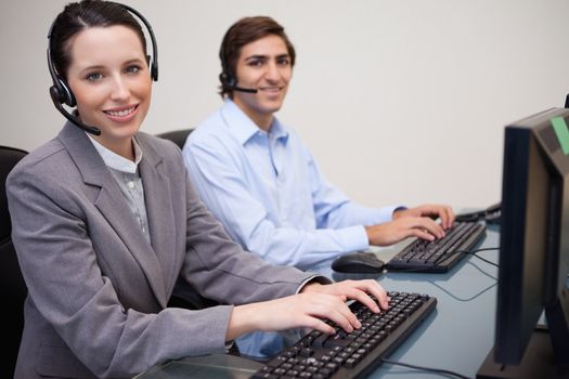 Side view of smiling young call center agents at work