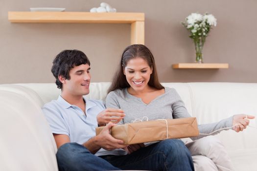 Young couple opening parcel on the sofa
