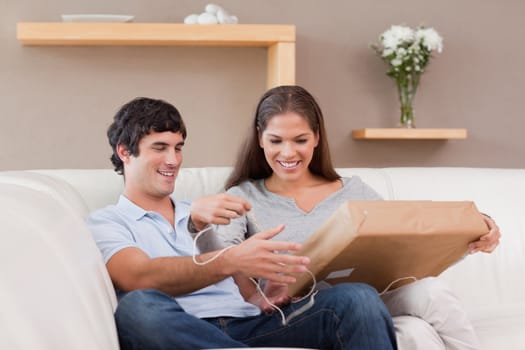 Young couple opening parcel on the couch