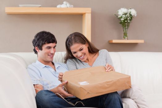 Young couple on the sofa opening parcel