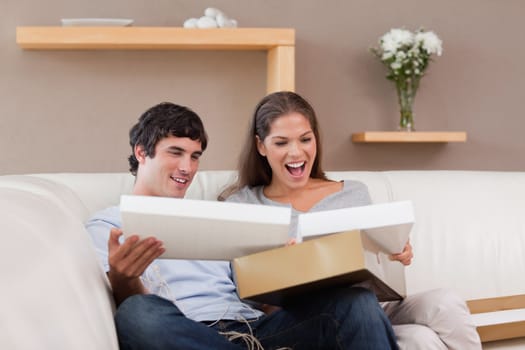 Young couple on the couch opening parcel