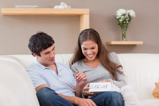Young woman opening present from her boyfriend on the sofa