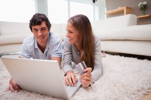 Young couple lying on the floor shopping online