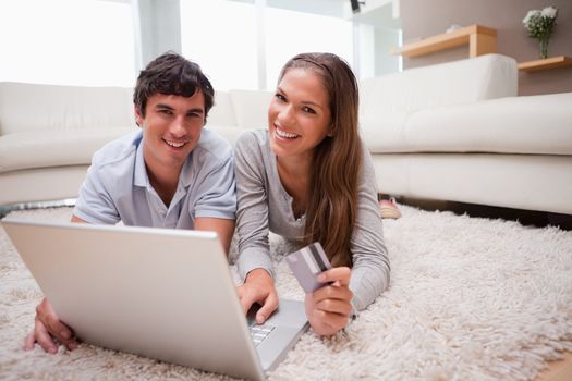 Young couple lying on the floor booking holidays online
