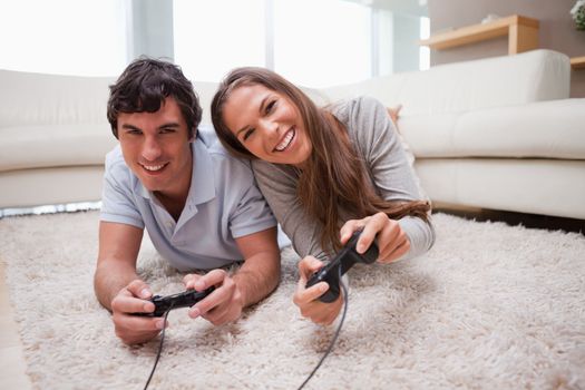 Young couple playing video games on the floor