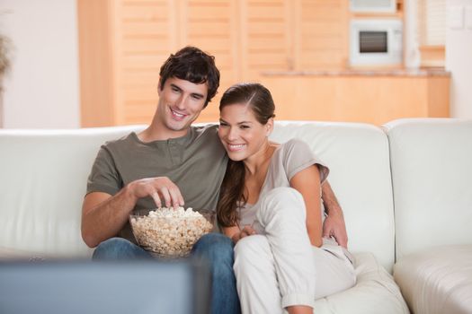 Young couple with popcorn on the sofa watching a movie