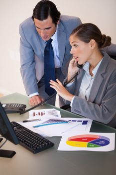 Young businesswoman getting a phone call while analyzing statistics