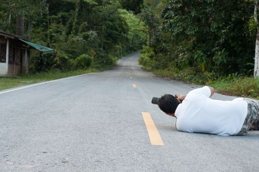 asian man photographer lay down and take a picture of the road