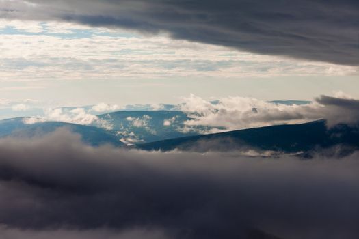 Clouds billowing over and between hills and mountains nature landscape.