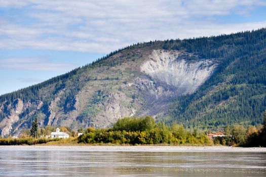 View of goldrush town of Dawson City and Moosehide Slide on hillside behind seen from Yukon River, Yukon Territory, Canada