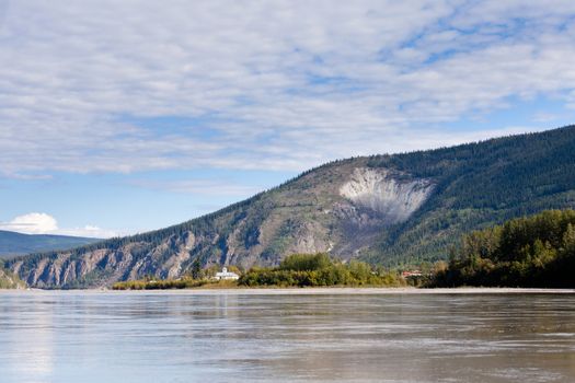 View of goldrush town of Dawson City and Moosehide Slide on hillside behind seen from Yukon River, Yukon Territory, Canada