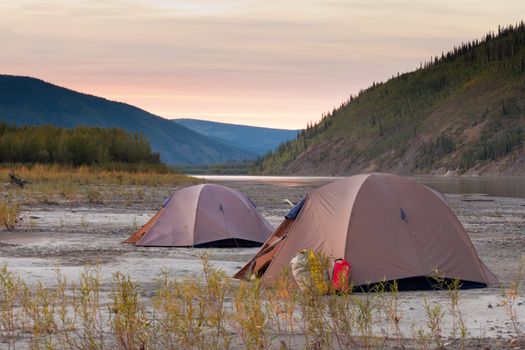 Two tents pitched on a sand bar alongside Yukon River, Yukon Territory, Canada, in remote boreal forest wilderness