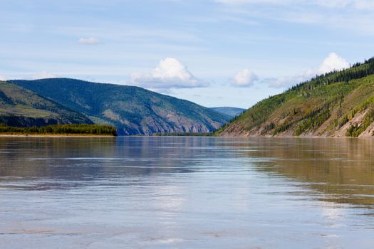 Boreal forest hills at river bank of Yukon River, Yukon Territory, Canada, near Dawson City forming a beautiful northern riverscape.