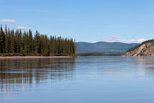 Boreal forest hills at river bank of Yukon River, Yukon Territory, Canada, near Dawson City forming a beautiful northern riverscape.