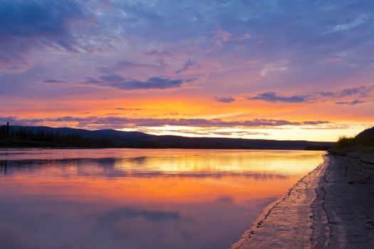 Beautiful sunset over wilderness of Yukon River, Yukon Territory, Canada, near Dawson City forming a northern riverscape.
