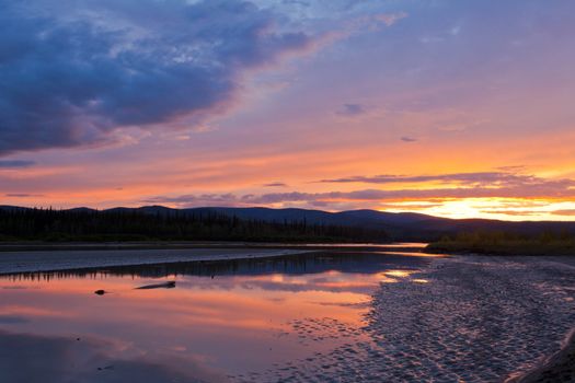 Beautiful sunset over wilderness of Yukon River, Yukon Territory, Canada, near Dawson City forming a northern riverscape.