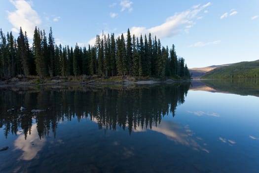 Boreal forest reflected on calm water surface of Steward River, central Yukon Territory, Canada, near eown of Mayo forming a beautiful northern riverscape.