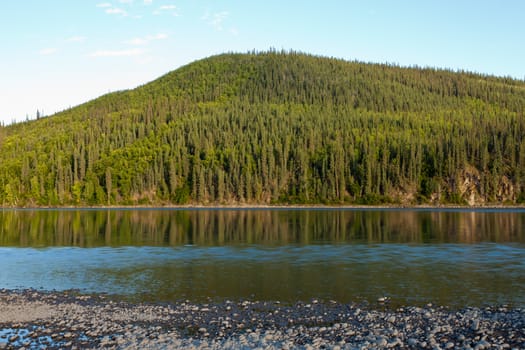 Boreal forest hills at river bank of Steward River, central Yukon Territory, Canada, near eown of Mayo forming a beautiful northern riverscape.