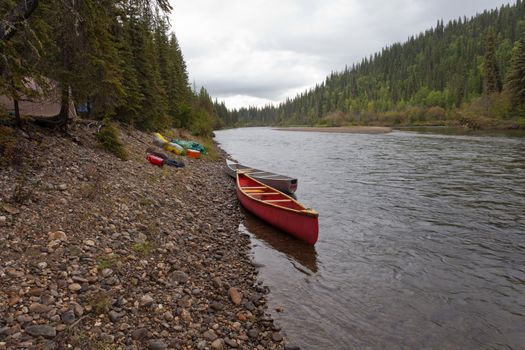Tent camp in boreal forest and canoes on paddle river trip on McQuesten River, Yukon Territory, Canada