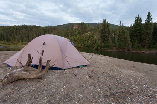 Tent pitched on a sand bar alongside McQuesten River, Yukon Territory, Canada, in remote boreal forest wilderness