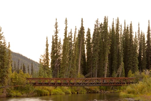 Old rotten abandoned steel bridge across McQuesten River in boreal forest taiga of central Yukon Territory, Canada