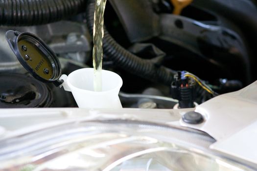 A yellow liquid is filling a container with engine parts in the background