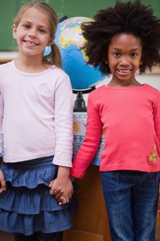 Portrait of schoolgirls holding hands in a classroom