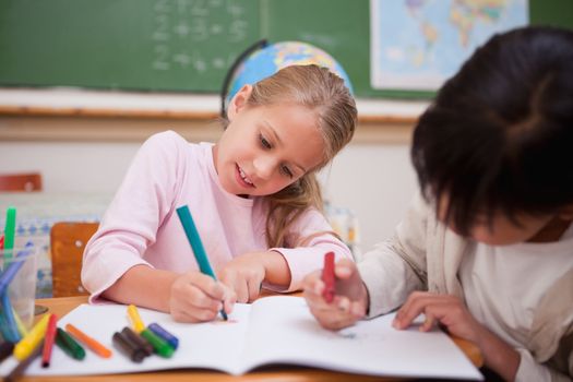 Cute schoolgirls drawing in a classroom