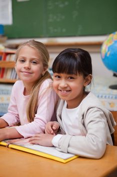 Portrait of smiling schoolgirls reading a fairy tale in a classroom