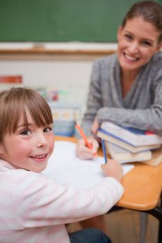 Portrait of a smiling teacher explaining something to her pupil in a classroom