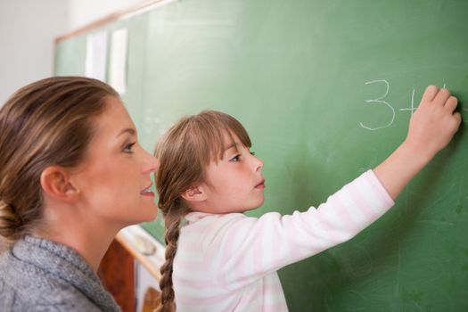 Teacher and a pupil making an addition on a blackboard