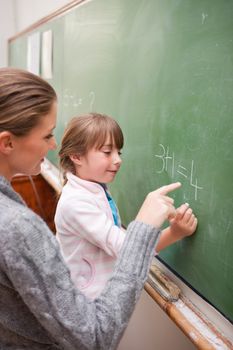 Portrait of a teacher and a pupil making an addition on a blackboard