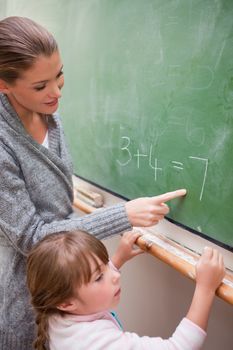 Portrait of a happy teacher and a pupil making an addition on a blackboard