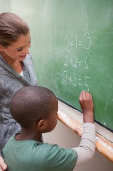 Portrait of a smiling teacher and a pupil making an addition in a classroom