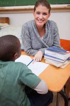 Portrait of a happy teacher explaining something to a pupil in a classroom
