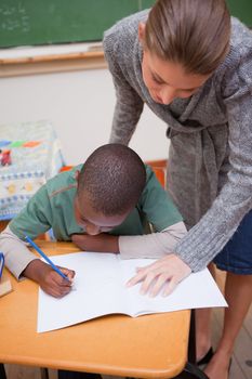 Portrait of a teacher explaining something to a focused schoolboy in a classroom