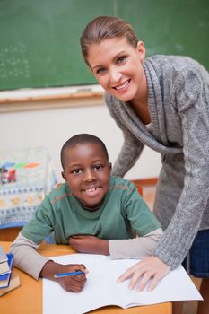 Portrait of a teacher explaining something to a smiling schoolboy in a classroom