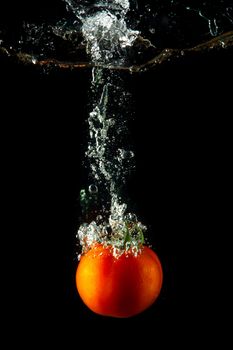 fresh tomato uder water on black background