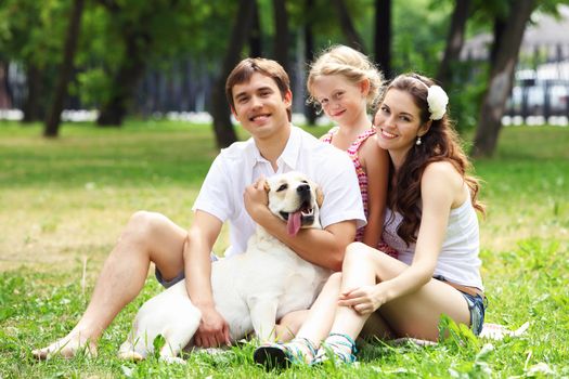 Young Family Outdoors in summer park with a dog