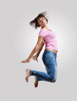 pretty modern slim hip-hop style woman jumping dancing on a colour background