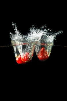 Colored red paprika in water splashes on black background