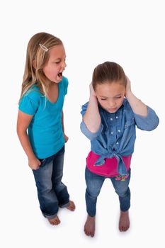 Portrait of an unhappy girl screaming at her friend against a white background