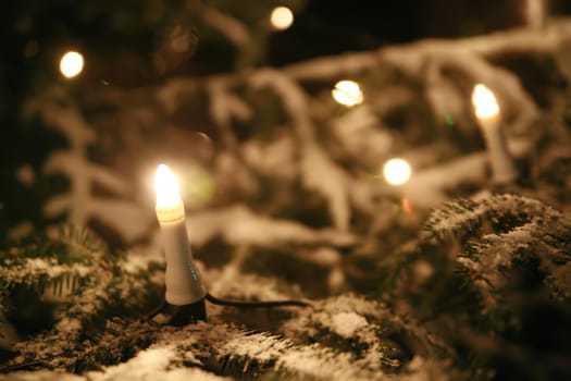 a christmas tree with electric candles outside