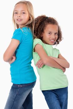 Portrait of happy girls standing back to back against a white background