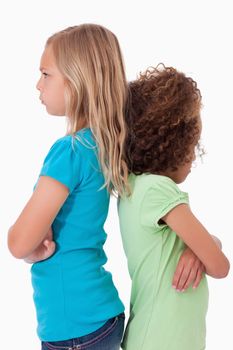 Portrait of unhappy girls standing back to back against a white background