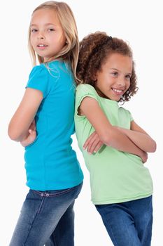 Portrait of smiling girls standing back to back against a white background
