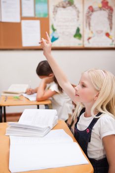 Portrait of a pupil raising her hand in a classroom